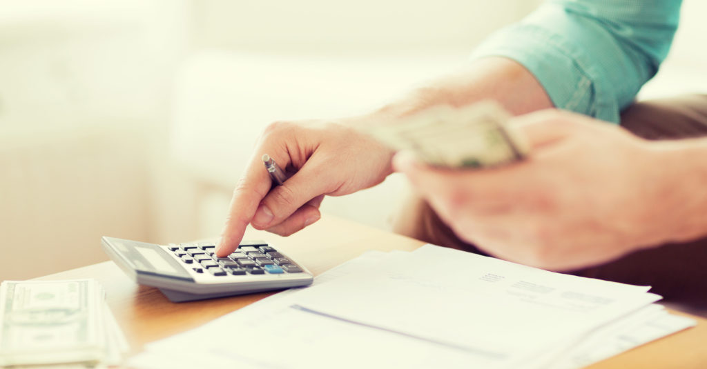 savings, finances, economy and home concept - close up of man with calculator counting money and making notes at home